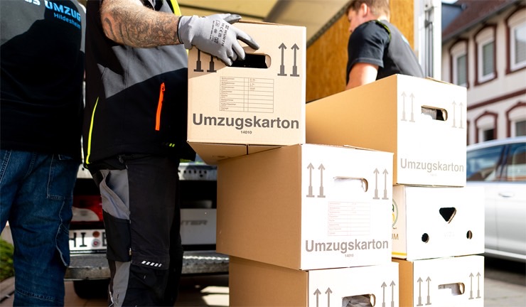 Nahaufnahme von Umzugskartons und Mitarbeitern von Express Umzug Hildesheim beim fachgerechten Verladen in einen Transporter für Betriebsauflösung, Firmenumzug oder Umzug.